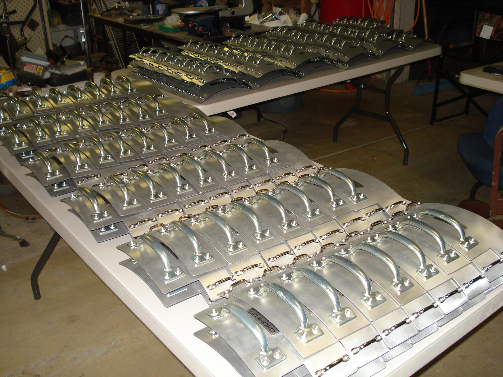 Rows of finished CINCH-N-LIFT handles laid out on workshop tables