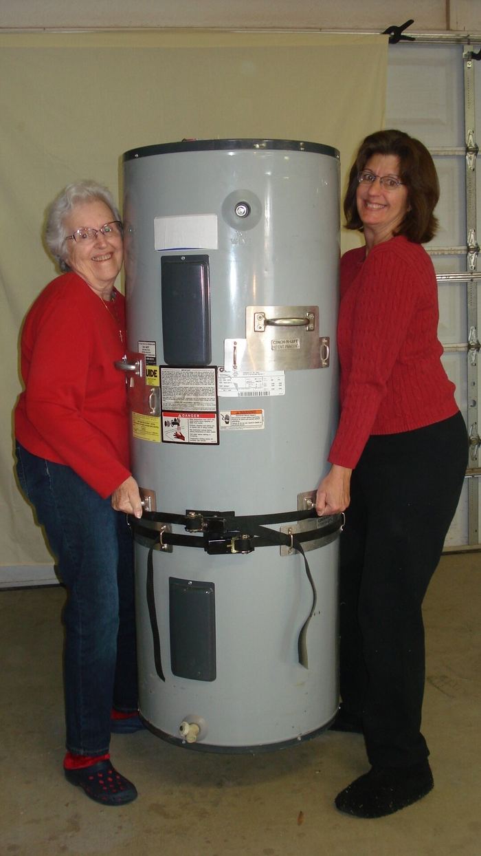 Two women lifting a water heater together by its handles